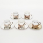 PORCELANA E AÇO INOX, cinco (5) xícaras para café, cilíndricas, tonalidade branca, arremates com frisos prateados, duas marcas distintas: RENNER e POZZANI, todas acompanham monture e pires sem marca aparente, sinais de uso, vide foto.