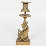 BRONZE, um (1) antigo castiçal, base trapezoidal retangular, corpo representando Grifo (criatura mitológica e lendária, originária das antigas culturas, Persas, Egípcias e da Mesopotâmia), bobeche vazada e relevada em perolados e elementos vegetalistas (se encontra bamba, demanda ajustes), fundição de excelente qualidade com mínimo de porosidade., possivelmente francesa, medindo 20 cm altura, vide foto.