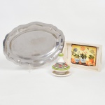 DIVERSOS, três (3) itens distintos: 1 travessa oval, confeccionada em aço inox, borda plissada, sem marca de manufatura aparente, medindo 30,5 x 20,5 cm; 1 bandeja retangular, ornada com lito policromada representando vaso de flores, confeccionada em MDF, origem São Luiz do Paraitinga, medindo 18 x 12 cm; 1 pote pequeno com tampa e presentoir, confeccionado em faiança, ornamentação policromada pintada a mão, marca na base não identificada, altura total 9,5 cm, todos os itens com sinais de uso, vide foto.