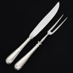 FAQUEIRO, conjunto trinchante para carne com dois (2) talheres: 1 faca e 1 garfo, manufatura WOLFF (tradição desde 1894), ornamentação relevada com guirlandas de tulipas, frisos e folhas, medindo a maior peça 28 cm comprimento, pontinha da lâmina em aço da faca quebrada, cabo em metal prateado, vide foto.