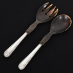 FAQUEIRO, conjunto para salada com dois (2) talheres: 1 colher e 1 garfo, manufatura WOLFF (tradição desde 1894), ornamentação relevada com guirlandas de tulipas, frisos e folhas, medindo a maior peça 23 cm comprimento, cabo em metal prateado, extremidades entalhada em chifre, vide foto.