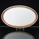 PORCELANA, uma (1) travessa oval, ornada com faixa na tonalidade bordo, generosos arremates a ouro, manufatura STEATITA (Campo Largo, PR, funcionou de 1954 a 1994), medindo 36,5 x 23,5 cm, sinais de uso, vide foto.
