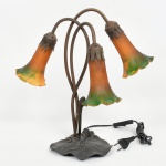 LUMINÁRIA, um (1) abat-jour para três lumes, padrão Art Nouveau, base relevada em elementos vegetalistas, cúpulas em vidro na tonalidade âmbar com mesclados em branco e borda drapeada, parte elétrica funcionando, medindo 40 cm altura, sinais de uso, vide foto.