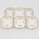 PORCELANA JAPONESA, seis (6) pratos quadrangulares com quinas chanfradas para sobremesa, ornamentação floral policromada, faixa na tonalidade creme, barrado da borda com silhueta vegetalista, arremates a ouro, manufatura NORITAKE (1858 - Japão assinou o Tratado de Amizade e Comércio com os EUA, Holanda, Rússia, Reino Unido e França; 1867 fim do Shogunato e início da era Meiji; 1876 - Morimura-Kumi formada em Tóquio para exportação Os Morimuras & The Okuras unidos, a Companhia Hinode se estabelece na cidade de Nova York para o varejo; 1879 - A Companhia Hinode fecha. Morimura Bros & Co., se estabelece em Nova York; 1880 - Hiroses juntou-se a Morimura-Kumi em Tóquio; 1882 - Morimura Bros & Co., decidiu ser o atacadista; 1884 Morimura-Kumi subcontrata atelieres de decoração em porcelana nas cidades de Tokyo, Nagoya e Kyoto; 1918 - Morimura-Kumi é reorganizada como Morimura Bros, Inc.; 1921 - Morimura Bros de New York é incorporada a Morimura Bros, Inc. De Tokyo; 1947 - Noritake Co., Inc. com sede em Nova York; 1981 - Nome japonês da Companhia alterado para Noritake Co. Limited), medindo 15 x 15 cm, sinais de uso, vide foto.