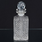 VIDRO, uma (1) licoreira retangular, incolor e translúcida, moldada em sulcos e bico de jaca, tampa adaptada lapidada em facetados, medindo 23 cm altura, sinais de uso, vide foto.