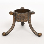 BRONZE, uma (1) base trípode, terminação macetada, ornamentação relevada em elementos vegetalistas, medindo 7 cm altura, vide foto.