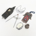 DIVERSOS, seis (6) objetos variados: 1 identificador para garrafa de bebida, confeccionado em aço, traz a legenda MARTINI; 1 porta-retratos oval, ornamentação relevada em flores, medindo 5,5 x 4 cm, confeccionado em resina e prateado; 1 antigo compasso, confeccionado em metal niquelado, medindo 11,5 cm; 1 caixa no formato de concha bivalve, encimada por cruz, medindo 3,5 cm, confeccionada em metal; 1 simbolo do Judaísmo e Islamismo confeccionado em metal esmaltado, representando Hamsá (Mão de Fátima); 1 parte de demolição em bronze no estado, medindo 13,5 cm, todos os itens com sinais de uso, vide foto.