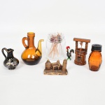 DIVERSOS, sete (7) itens: 1 galheta sem a tampa, confeccionada em vidro na tonalidade âmbar, translúcida, medindo 10 cm altura; 1 polvilhador confeccionado em vidro âmbar e translúcido, formato de barrica, tampa em polímero, medindo 8 cm; 1 vaso miniatura, confeccionado em faiança ou louça, souvenir da Grécia, ornado com figuras policromadas sobre fundo preto, arremates a ouro; 1 vidro, incolor e translúcido com diversos espetos para petiscos, confeccionados em madeira, extremidades ornadas com esferas coloridas; 1 miniatura representando fonte, souvenir de Orense, confeccionada em madeira, medindo 8,5 cm; 1 escultura metálica representando galo, esmaltada em policromia, souvenir de Barcelos, medindo 5 cm altura; 1 escultura representando pontos turísticos italianos, confeccionada em resina, medindo 7 x 3,5 x 5 cm, vide foto.