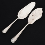FAQUEIRO, dois (2) talheres distintos para servir, confeccionados em metal prateado, ornamentação relevada em frisos e volutas, manufatura PRATA WOLFF 90 (tradição desde 1894), sendo: 1 espátula para peixe e 1 espátula para torta ou bolo, ambas com sinais de uso, vide foto.