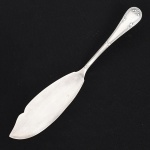 FAQUEIRO, uma (1) espátula para servir peixe, confeccionada em metal prateado, manufatura FRACALANZA (tradição desde 1884), ornamentação no padrão Art Nouveau, relevada em frisos e folhas terminando em laçarote, medindo 28 cm comprimento, sinais de uso, vide foto.