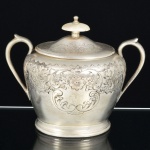 METAL PRATEADO INGLÊS, um (1) açucareiro com tampa, ornamentação burilada e cinzelada em elementos vegetalistas, pega da tampa em polímero, alças curvilíneas, marca representada por trevo com estrelas dentro das pétalas (fundada em 1801 por Mary Barker, como Barker Bros, logo depois o negócio foi continuado pelo filho William Barker em parceria com Creed; mudou de nome várias vezes: Barker & Creed; William & Matthias Barker; Barker Brothers; Barker Brothers Silversmiths Ltd.; Barker Ellis Silver Company Ltd.), ladeado pelas letras EP BM (electro plate britain metal), Made in England, medindo 13 cm altura, sinais de uso, vide foto.