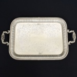 METAL PRATEADO INGLÊS, uma (1) imponente bandeja, ornamentação burilada e cinzelada em elementos vegetalistas, borda canelada, alças relevadas em convchas, volutas e elementos vegetalistas, marca representada por trevo com estrelas dentro das pétalas (fundada em 1801 por Mary Barker, como Barker Bros, logo depois o negócio foi continuado pelo filho William Barker em parceria com Creed; mudou de nome várias vezes: Barker & Creed; William & Matthias Barker; Barker Brothers; Barker Brothers Silversmiths Ltd.; Barker Ellis Silver Company Ltd.), ladeado pelas letras EP BM (electro plate britain metal), Made in England, medindo 51 x 39 cm fora as alças, sinais de uso, vide foto.
