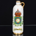 PORCELANA, uma (1) garrafa cilíndrica, pintada a mão com Brasão do Império Brasileiro, legenda RHUM, manufatura SÃO PAULO (São Caetano do Sul, SP, 1940 a 1980, inicialmente como Teixeira Barreto & Companhia, a partir de 1946 como Virgílio Teixeira & Irmão), marca possessória escrita a lápis na base, arremates a ouro, medindo 26,5 cm altura, sinais de uso, vide foto.