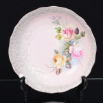 PORCELANA, uma (1) fruteira de pé baixo, pintada a mão com rosas em policromia pelo atelier ZAIRA, manufatura SCHMIDT (Pomerode, SC; Mauá, SP; Campo Largo, PR, fundada em 1945, ainda em atividade, maior fábrica de porcelana da América Latina), bicado acentuado na borda, medindo 19 cm diâmetro, vide foto.