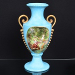 PORCELANA, uma (1) imponente ânfora com ornamentação pintada a mão em policromia representando cena de galanteio baseada na obra de  FRAGONARD (Jean Honoré Fragonard, Grasse 1732 Paris 1806, pintor, desenhista e gravurista francês, estilo Rococó, conhecido pela exuberância e hedonismo de sua obra, pinturas do gênero com atmosfera de intimidade e erotismo), sobre fundo na tonalidade azul, arremates a ouro, atelier IZA 1970, manufatura REAL (Mauá, SP, 1943 a 1994), medindo 49 cm altura, vide foto.