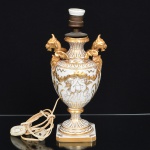 PORCELANA, uma (1) base de abat-jour para um lume, formato de ânfora, alças na forma de Grifos (criatura mitológica e lendária, originária das antigas culturas, Persas, Egípcias e da Mesopotâmia), ornamentação relevada em anjos, generosos arremates a ouro, parte elétrica não testada, selo da La Casa Del Regalo, Rincon 619, Made in France, medindo 33 cm altura, vide foto.