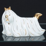 ESCULTURA, uma (1) representando cachorro, confeccionada em porcelana branca, arremates a ouro, apliques em cristais facetados, selo marcado: PASTA DE LIMOGES P. T. CERTIFICADO DE QUALIDADE  SWAROVSKI CRYSTALS, medindo 20,5 cm comprimento, vide foto.