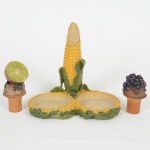 DIVERSOS, uma (1) base para galheteiro, confeccionada em resina policromada, formato de espiga de milho,acompanham duas tampas em madeira adornadas em resina policromada representando limão e cacho de uva, medindo12,5 cm altura, vide foto.