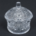 VIDRO, um (1) pequeno porta confeitos com tampa, incolor e translúcido, moldado em gomos, pega da tampa com facetado hexagonal afinado para cima, medindo 10 cm altura, sinais de uso, vide foto.