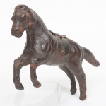 ESCULTURA, uma (1) animalista representando cavalo encilhado, confeccionada em couro e papel marche, além de taxas, possui pequenas perdas e defeitos, medindo 23 cm comprimento, vide foto.