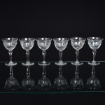 VIDRO, sete (7) taças de pé alto para vinho do Porto, incolores e translúcidas, bojo com singela lapidação vegetalista, fuste no formato de balaustre, base em bolacha, medindo 10 cm altura, sinais de uso, vide foto.