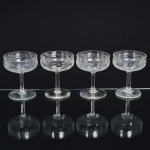 VIDRO, quatro (4) taças de pé alto para champanhe ou espumante, incolores e translúcidas, bojo com singela lapidação vegetalista, fuste cilíndrico, base em bolacha, medindo 10 cm altura, sinais de uso, vide foto.