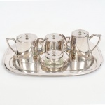 AÇO INOX, baixela para chá e café com cinco (5) itens: 1 bandeja; 2 bules; 1 açucareiro e 1 manteigueira com recipiente cilíndrico em vidro, incolor e translúcido, pegas das tampas no formato de carrapeta, manufatura BELPRATA, medindo a maior peça 44,5 x 32,5 cm, todos os itens com sinais de uso, vide foto.