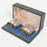 METAL PRATEADO, par (2) porta guardanapos, vazados em elementos vegetalistas estilizados, marca puncionada, acondicionados em estojo, vide foto.