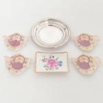 DIVERSOS, seis (6) itens: 1 covilhete retangular, pintado a mão com flores em policromia, arremates a ouro, atelier Maria Deolinda, ano 1967, marca PORBRAS (Guarulhos, SP, anos 60 até 1991), medindo 10 x 7,5 cm; 1 porta garrafa em metal prateado, borda em degrau, sem marca de manufatura aparente, medindo 13,5 cm diâmetro; 4 descansos para saquinhos de chá, confeccionados em polímero policromado, formato de bule, medindo 9,5 x 7,5 cm, todos os itens com sinais de uso, vide foto.