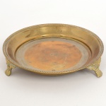 BRONZE, uma (1) salva circular, borda relevada em corda, fundo ornado com barrado executado por carretilhas, pés relevados em elementos vegetalistas terminando em garras, medindo 15 cm diâmetro, sinais de uso, vide foto.