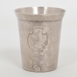 METAL PRATEADO, um (1) antigo copo, ligeiramente obcônico, liso, detalhe ornado a buril em escudo e flores , marca parcialmente legível da manufatura EBERLE (Abramo Eberle 1880, Monte Magrè 1945, Caxias do Sul, veio com uma das primeiras levas de imigrantes italianos para o Brasil em 1884 junto com seus pais Giuzeppe Eberle e Luigia Zanrosso, seu pai abriu uma pequena funilaria mas como tinha que trabalhar na lavoura quem cuidava era a mãe e o pequeno Abramo ajudava na funilaria; em 1896 quando o pai resolveu vender a funilaria para concentrar os esforços da família na lavoura Abramo, com 16 anos de idade, se propôs a comprá-la do pai, em 1918 já com o nome Abramo Eberle & Cia iniciou a fabricação de talheres e utensílios de mesa, morreu em 1945 com 65 anos de idade e os filhos deram continuidade aos negócios até 1984 quando venderam para o Grupo Zivi), medindo 8 cm altura e 7 cm diâmetro, sinais de uso, vide foto.