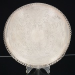 METAL PRATEADO, uma (1) salva com borda e pés em gradil vazado, fundo burilado em pérgulas e elementos vegetalistas, medindo 25,5 cm diâmetro, sinais de uso, vide foto.