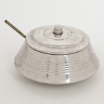 AÇO INOX, uma (1) farinheira com tampa, possui a concha, ornada com reentrâncias horizontais, marca ROYAL INOX, medindo 15 cm diâmetro, sinais de uso, vide foto.