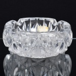 CRISTAL, um (1) cinzeiro, grosso, incolor e translúcido, modelado em geométricos e bico de jaca, fundo em dália, medindo 15 cm diâmetro e 6 cm altura, sinais de uso, vide foto.