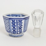 VIDRO E PORCELANA, dois (2) itens: 1 tampa para garrafa, incolor e translúcida, lapidação facetada, medindo 98 cm altura; 1 recipiente hexagonal com ornamentação pintada a mão na técnica blue and white, sem marca de manufatura aparente, possivelmente de origem chinesa, partida ao meio e colada, medindo 8,5 cm diâmetro e 7 cm altura, sinais de uso, vide foto.