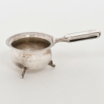 METAL PRATEADO, um (1) suporte individual para infusão de chá, formato de caldeirão e com alça, base trípode, sem marca de manufatura aparente, medindo 6 cm diâmetro mais a alça, borda canelada, sinais de uso, vide foto.
