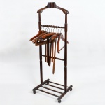 MOBILIÁRIO, um (1) criado mudo confeccionado em madeira torneada, padrão eclético, com duas traves paralelas com amarração em barras cilíndricas, cachaço anatômico, base em gradil para colocar os sapatos, medindo 116 cm altura, acompanham 10 cabides em madeira de diversas manufaturas e modelos variados, todos os itens com sinais de uso, vide foto.