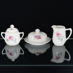 PORCELANA, três (3) itens com ornamentação floral policromada, arremates a ouro, modelagem canelada na vertical, sem marca de manufatura aparente, sendo: 1 cremeira; 1 açucareiro e 1 manteigueira, medindo a maior peça 13,5 cm diâmetro, sinais de uso, vide foto.