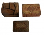 Lote composto por três caixas antigas decorativas, sendo: uma caixa revestida em couro com costuras aparentes e fecho metálico, uma caixa em marchetaria policromada com interior forrado em tecido vermelho, e uma caixa laqueada com decoração floral dourada. Peças de caráter decorativo e colecionável, apresentando sinais naturais do tempo. Medida da maior 12 cm.
