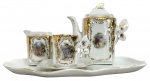 Conjunto de café em porcelana decorativa, composto por bule, leiteira, xícara com pires e bandeja. Peças em porcelana branca ricamente ornadas com aplicações em douração e reservas com cenas galantes em estilo europeu, além de delicadas asas em forma de borboleta. Bandeja de contorno ondulado acompanhando o conjunto. Medida do maior 25cm x 21cm.