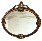 FRANÇA - Espelho oval de parede com estrutura em madeira nobre entalhada e dourada, ricamente ornado com volutas e elementos florais em relevo, encimado por elegante frontão decorativo. Espelho antigo com sinais do tempo (oxidação no mercúrio), característicos da idade. Estilo francês. Mede aprox. 74 x 77 cm.