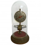 Relógio de mesa antigo, mecanismo eletromagnético aparente, com mostrador em algarismos romanos e ponteiros em destaque. Estrutura metálica montada sobre base circular e protegido por cúpula de vidro. Marca Tagus no mostrador. Mede 29 cm.