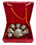 Conjunto para chá oriental em porcelana, ricamente decorado com cenas orientais policromadas e detalhes dourados, composto por bule com tampa e seis pequenas xícaras. Acompanha caixa original revestida em tecido vermelho com fechos. Marca oriental na base. Possui ausência. Medida da caixa 20 x 16 cm.