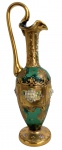 VENEZA - Jarro em cristal veneziano verde, ricamente decorado com douração e aplicações florais esmaltadas em relevo, apresentando elegante ornamentação em estilo rococó. Corpo bojudo com pescoço alongado, bocal ondulado e alça alta em forma de cisne, sobre base circular decorada. Peça de grande efeito ornamental, inspirada na tradição vidreira de Veneza. Mede 25 cm.