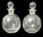 Par de garrafas em cristal artístico, de formato globular, decorados com delicada gravação em motivos de estrelas lapidadas. Acompanham tampas originais facetadas, também em cristal. Base com marca Margareth Duncan, tradicional manufatura ligada à produção de cristais artísticos. Peças elegantes, provavelmente destinadas a licor, com acabamento refinado e boa transparência do cristal. Mede 17cm de altura.