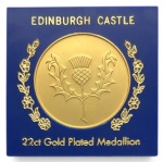 Medalhão comemorativo Edinburgh Castle, com banho de ouro 22k, apresentando no anverso o castelo em relevo e, no reverso, cardo escocês estilizado. Acondicionado em embalagem original. Peça decorativa de coleção, sem teor em ouro maciço. Mede 6 x 6 cm com a proteção acrílica.