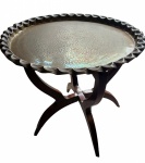 Mesa marroquina em metal martelado removível com bordas onduladas apoiada sobre base de madeira articulada conhecida como "pés de aranha". Medidas 55cm de diâmetro e altura de 50cm. VEJA FOTO EXTRA.