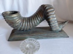 Castiçal em madeira nobre, em formato de chifre de carneiro, com acabamento de pátina envelhecida. Acompanha suporte graduado para vela em vidro decorado fosco. Medidas: 17 cm de altura x 38 x 12 cm de base.