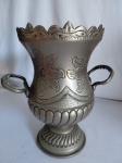 Vaso decorativo em metal fosco, com detalhes cinzelados em motivos florais e arabescos em alto relevo. Alças laterais. Formato de ânfora. Medidas: 23 cm de altura x 20 cm x 18 cm de diâmetro do bojo.