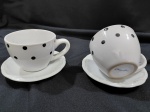 2 xícaras chá em porcelana esmaltada branca com bolinhas  pretas por todo corpo.